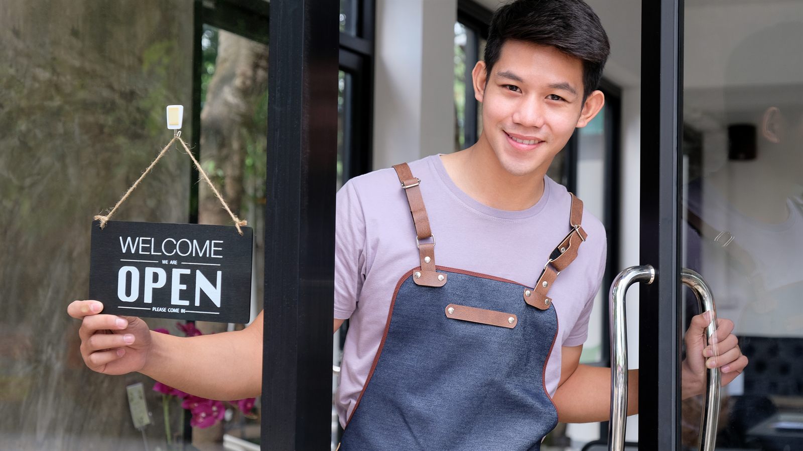 A Balagtas small-business owner welcoming customers with a WELCOME / OPEN sign at their store door